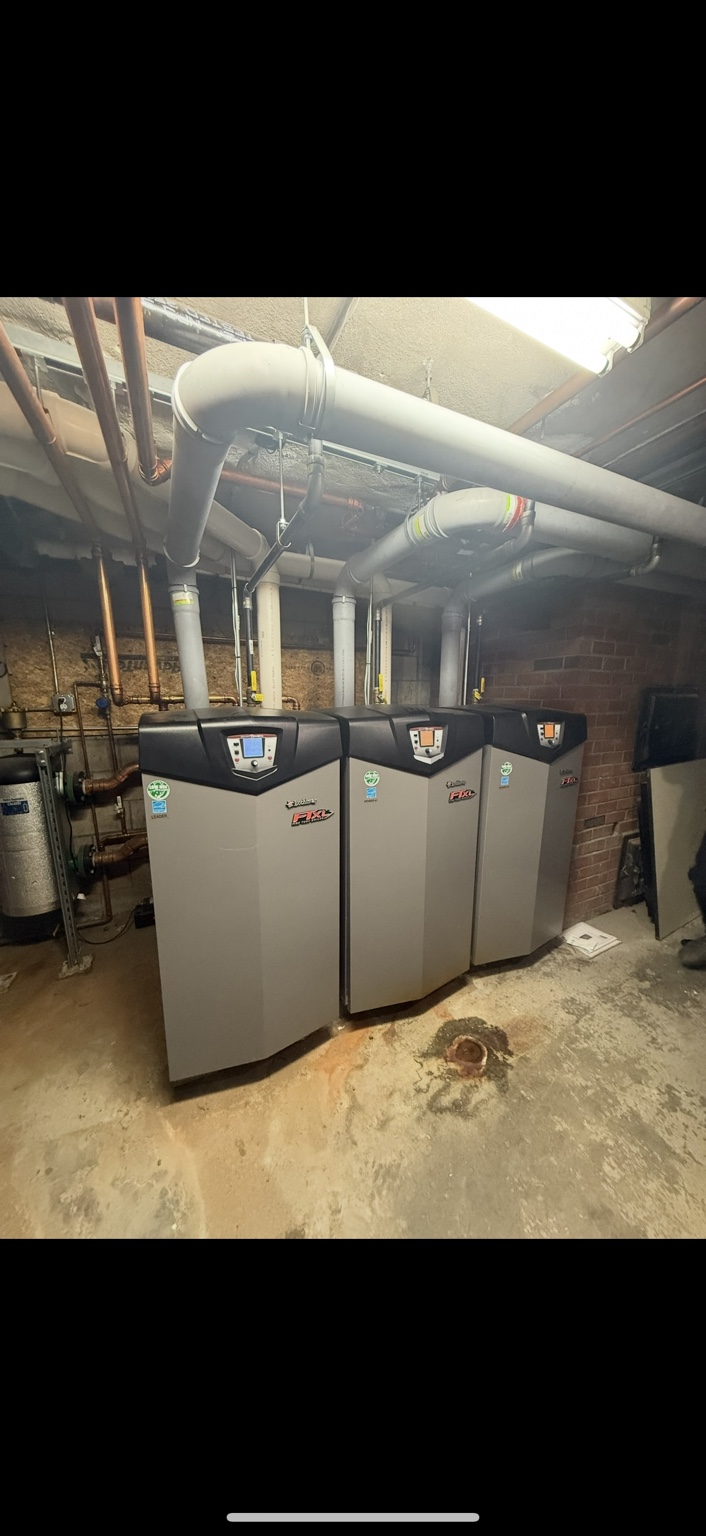 Three high-efficiency boilers installed in a mechanical room by Boyle Plumbing Solutions