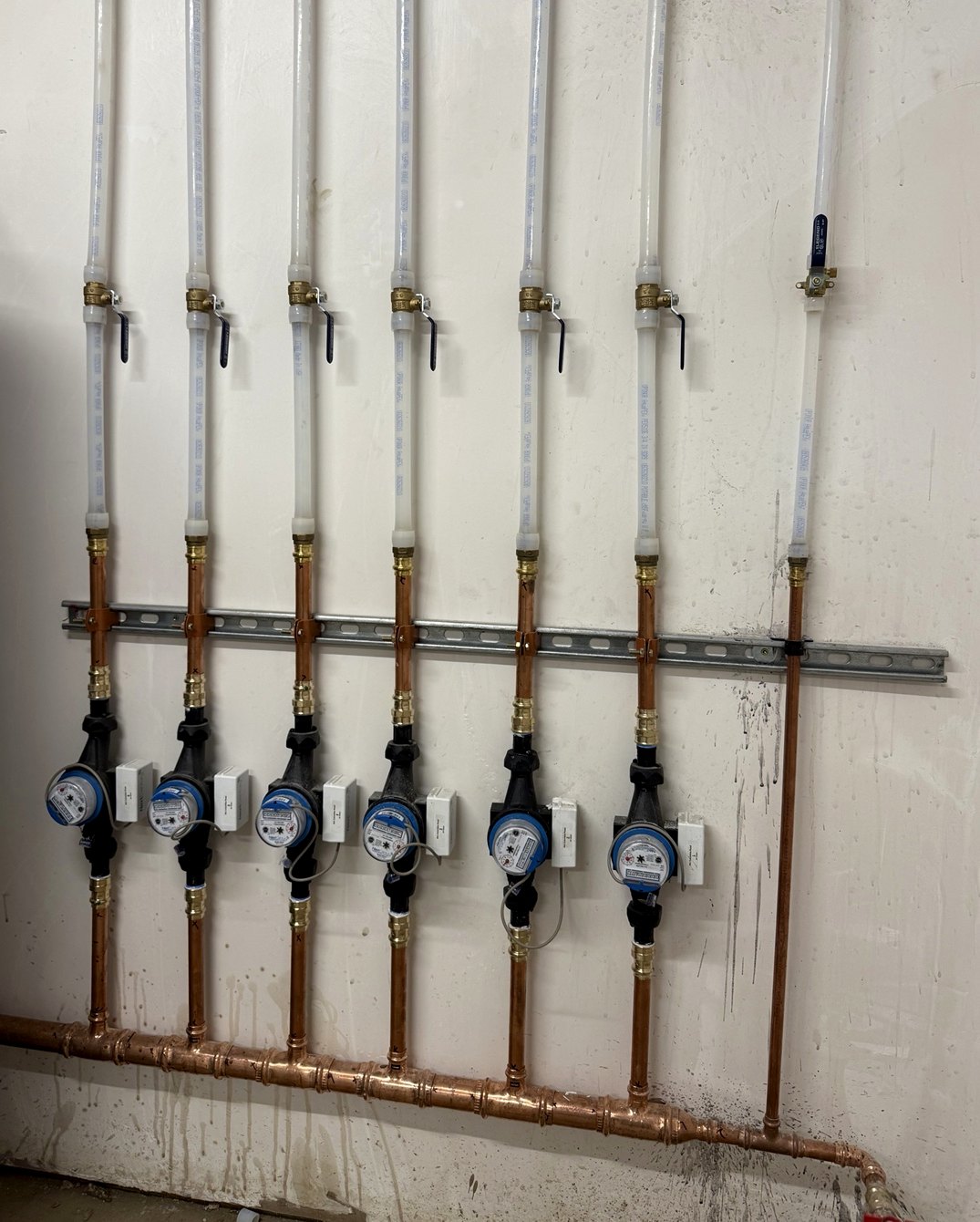 Well-aligned plumbing meter manifold with multiple vertical risers and copper piping