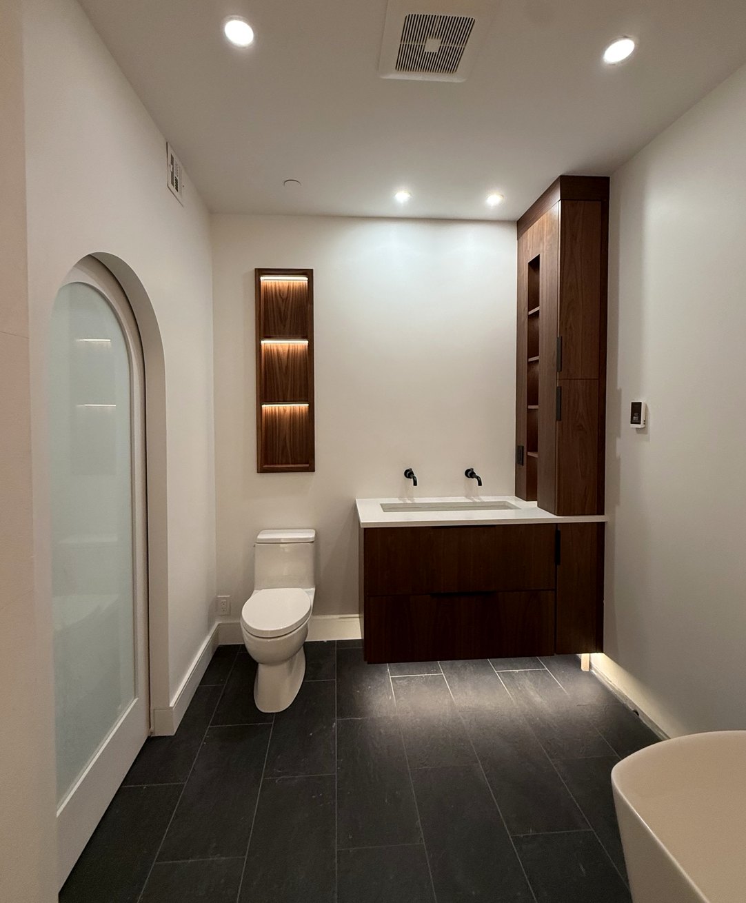 Finished contemporary bathroom featuring custom wood vanity, floating fixtures and warm accent lighting
