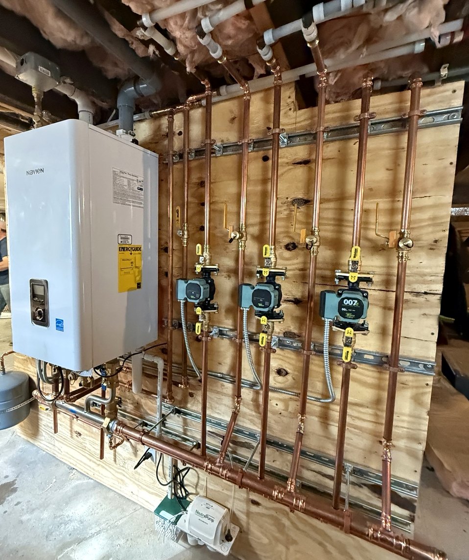 Navien boiler installation with neatly routed copper hydronic heating pipes and circulator pumps